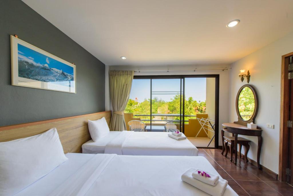 Baan Grood Arcadia Resort & Spa في بان كروت: غرفة فندقية بسريرين وبلكونة