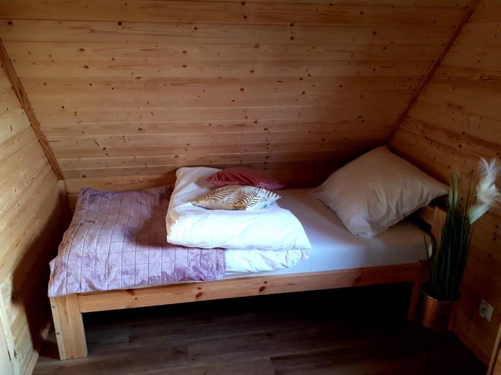 a bed in a wooden room in a cabin at Domki OstoYa Bieszczady/Solina in Myczkowce