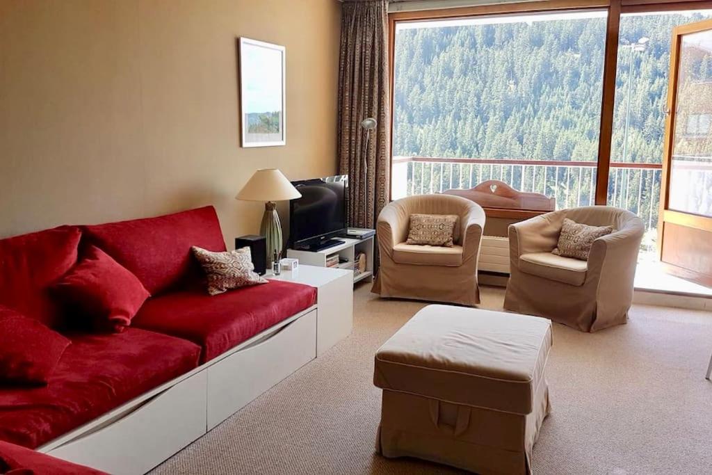 uma sala de estar com um sofá vermelho e cadeiras em L'Ariondaz - Appartement au centre du village, proche des pistes, avec parking em Courchevel