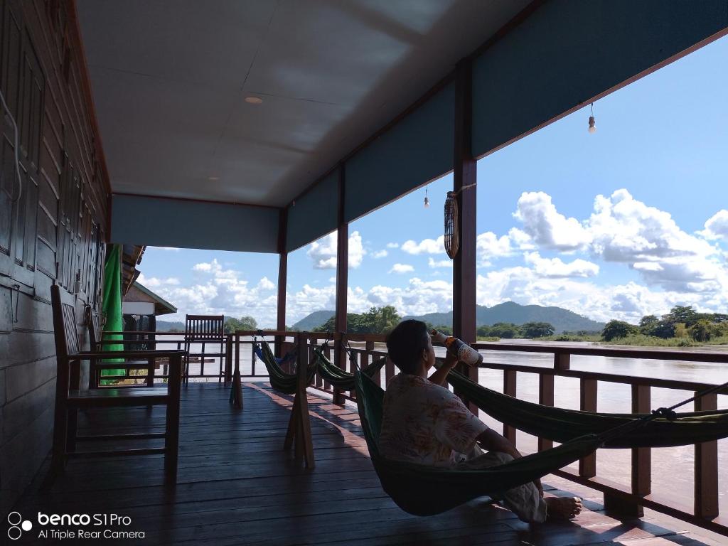 un homme et une femme assis dans un hamac sur une terrasse couverte dans l'établissement Namknong view, à Don Det