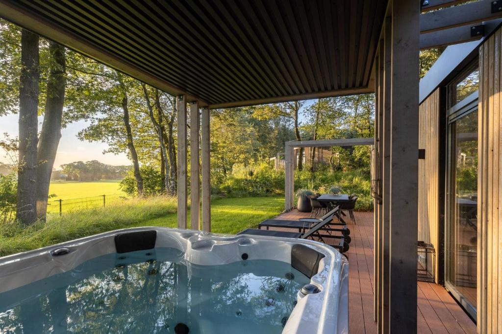 a hot tub on the patio of a house at Zicht op Twente - Spa lodges in Markelo