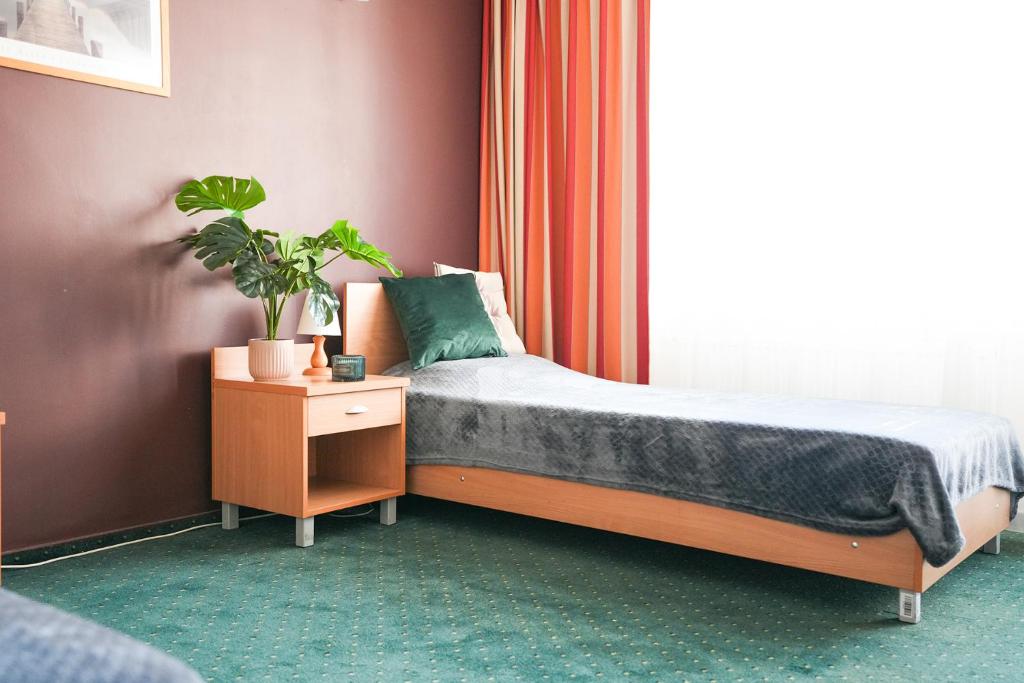 a bedroom with a bed and a plant and a window at Hotel Wilanów in Warsaw