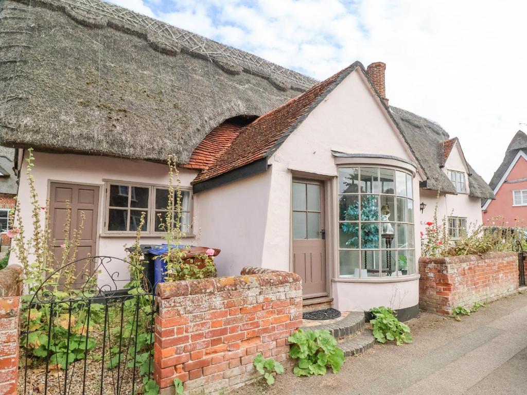 a cottage with a thatched roof and a brick fence at The Nook in Cavendish