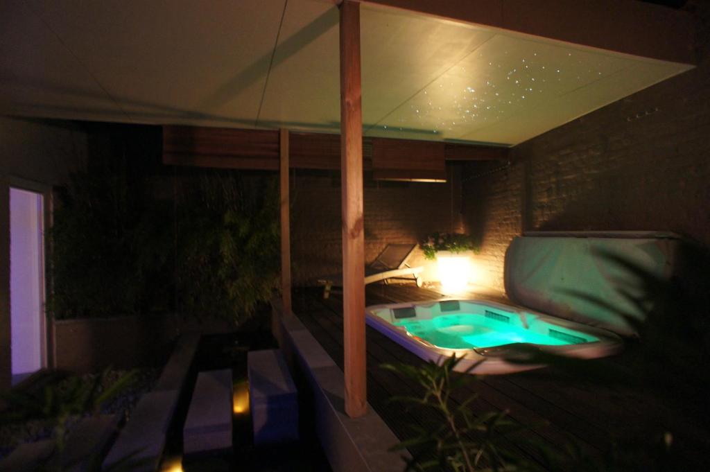 a patio with a hot tub and an umbrella at B&B Wellness Yoake in Ypres