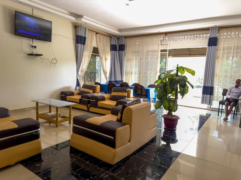 a waiting room with couches and a tv at Contra Hotel in Jinja
