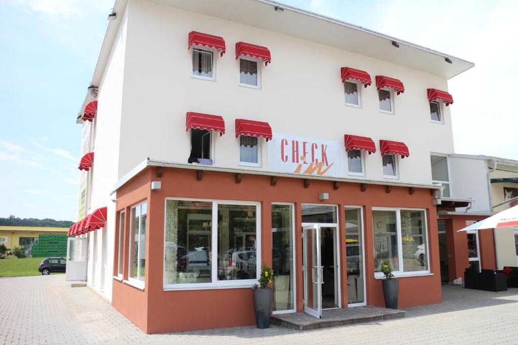 un edificio blanco y rojo con un letrero. en Hotel Checkin, en Gleisdorf