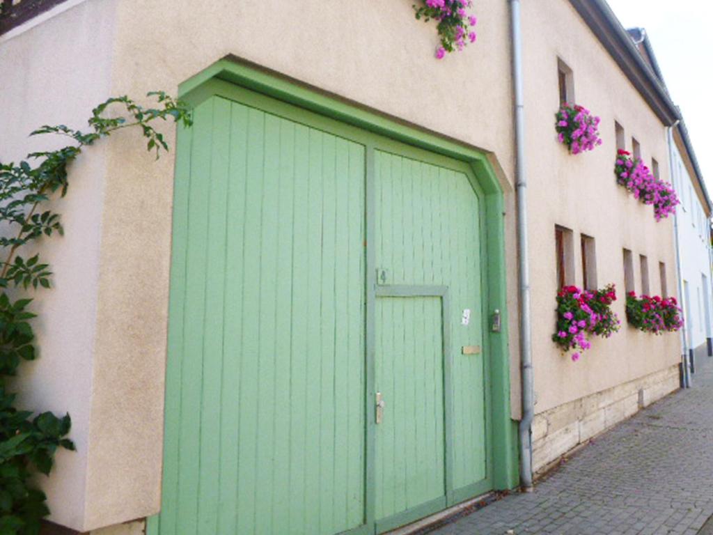 una porta verde sul lato di un edificio con fiori di Ferienwohnung Familie Mergner a Bad Langensalza