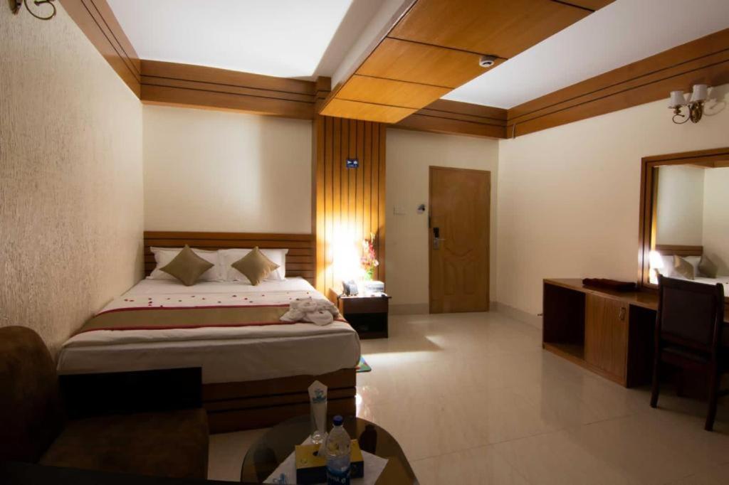 a bedroom with a bed and a desk and a mirror at Hotel Orion International in Jessore