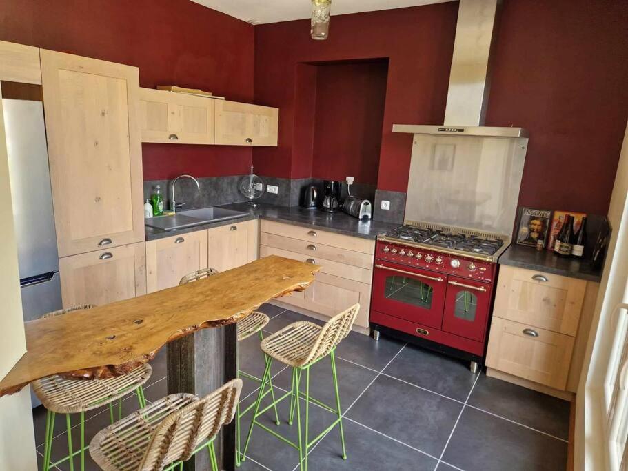 Il comprend une cuisine équipée d'une table en bois et d'une cuisinière rouge. dans l'établissement Maison Les Roses, à Marmagne