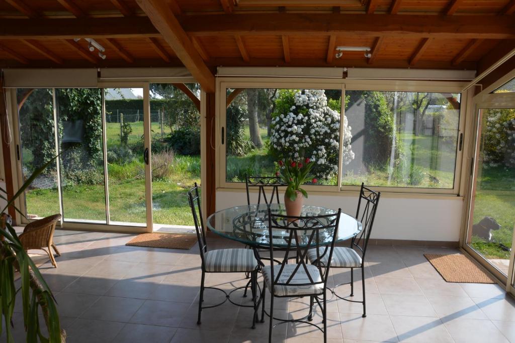 a screened in porch with a glass table and chairs at La Villa Bernard in Varennes-sur-Loire