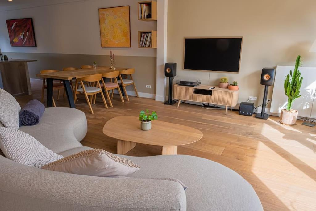 a living room with a couch and a tv and a table at Beautiful house close to Amsterdam Beach and Haarlem in Aerdenhout