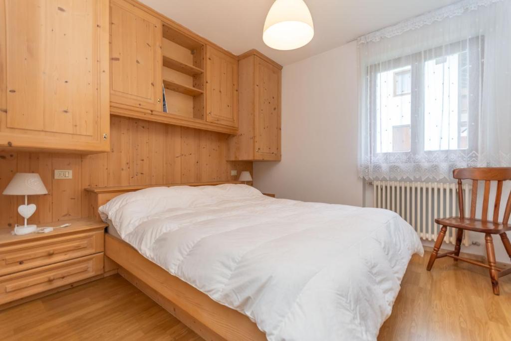 a bedroom with a bed with wooden cabinets and a chair at Casa Alice in Falcade
