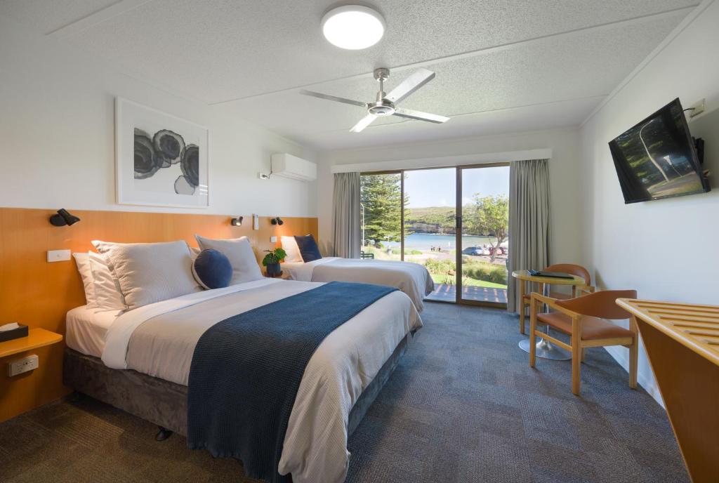 a hotel room with two beds and a balcony at Loch Ard Motor Inn in Port Campbell