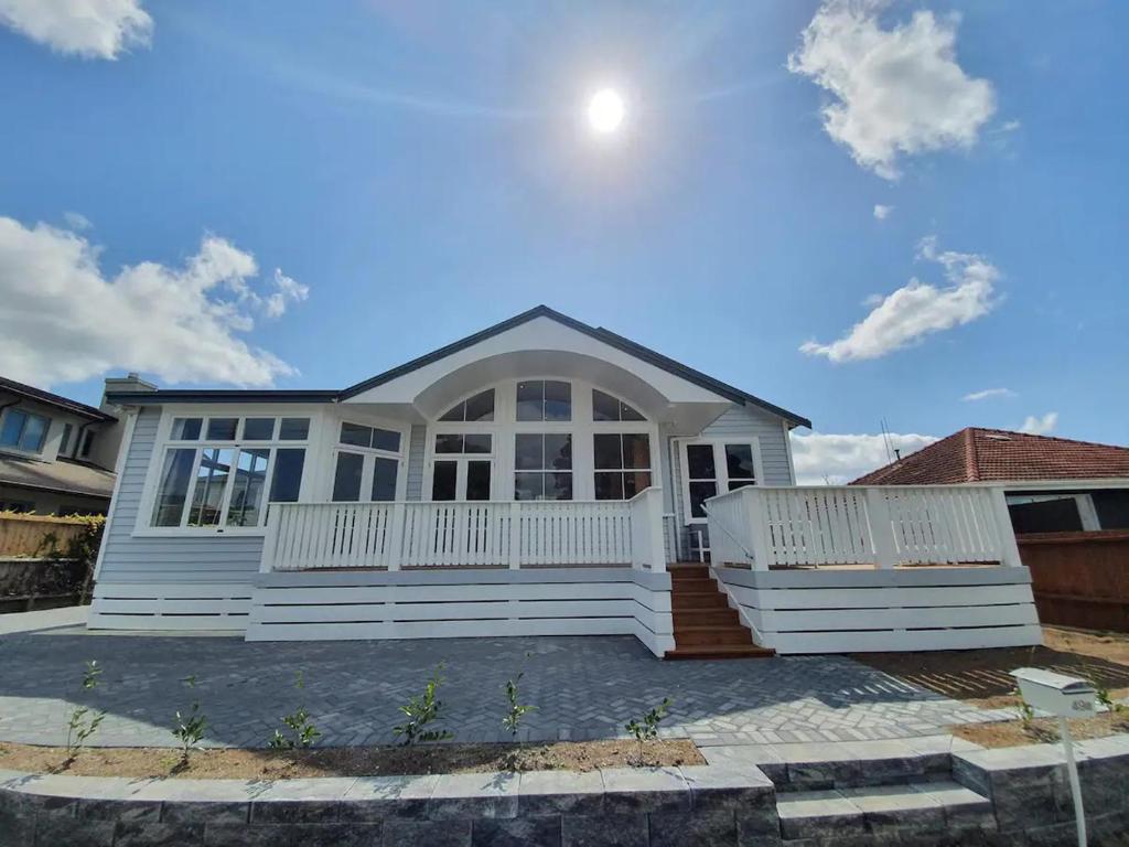 a white house with a front porch at Tauranga - Big, beautiful Villa on the water! in Tauranga