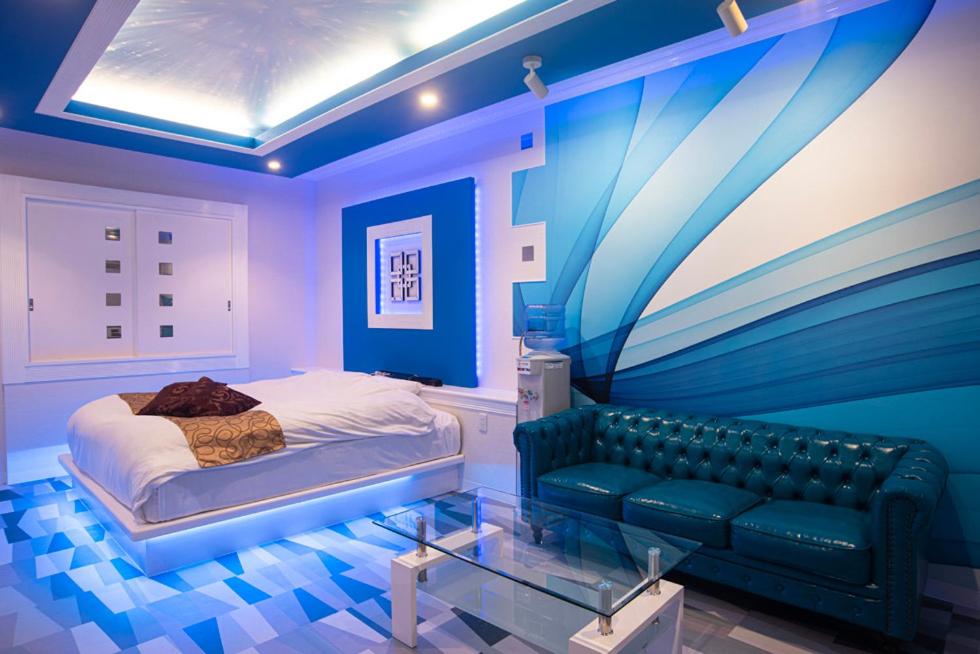 Dormitorio azul con cama y sofá en Hotel Bypass (Adult Only), en Koriyama