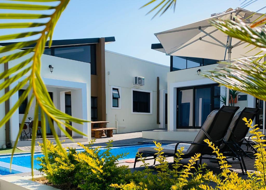 a villa with a swimming pool and a house at Essence Lifestyle Self-Catering Accommodation in Windhoek