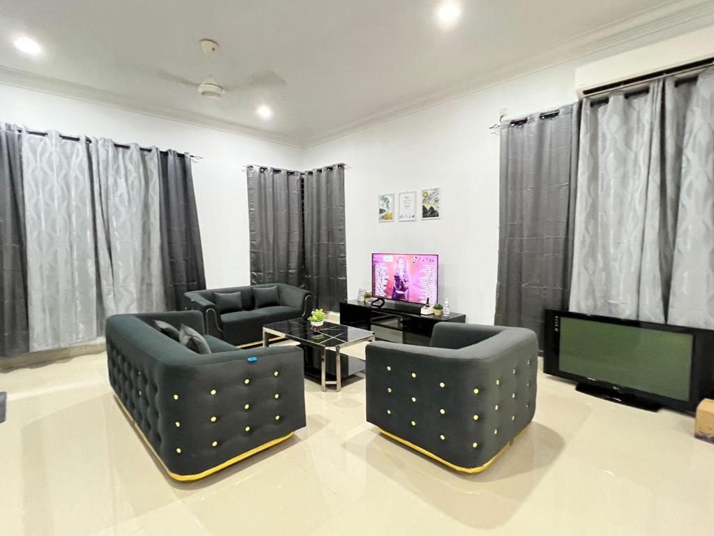 - un salon avec deux chaises et une télévision dans l'établissement EMPIRE LUXURY HOMESTAY PAKA, à Paka