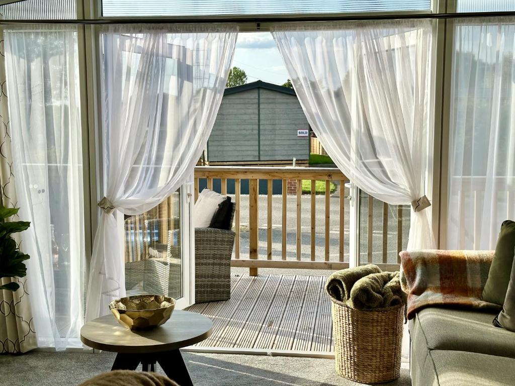 eine abgeschirmte Veranda mit weißen Vorhängen und einer Couch in der Unterkunft Oakland Lodge with Hot Tub and free parking in York