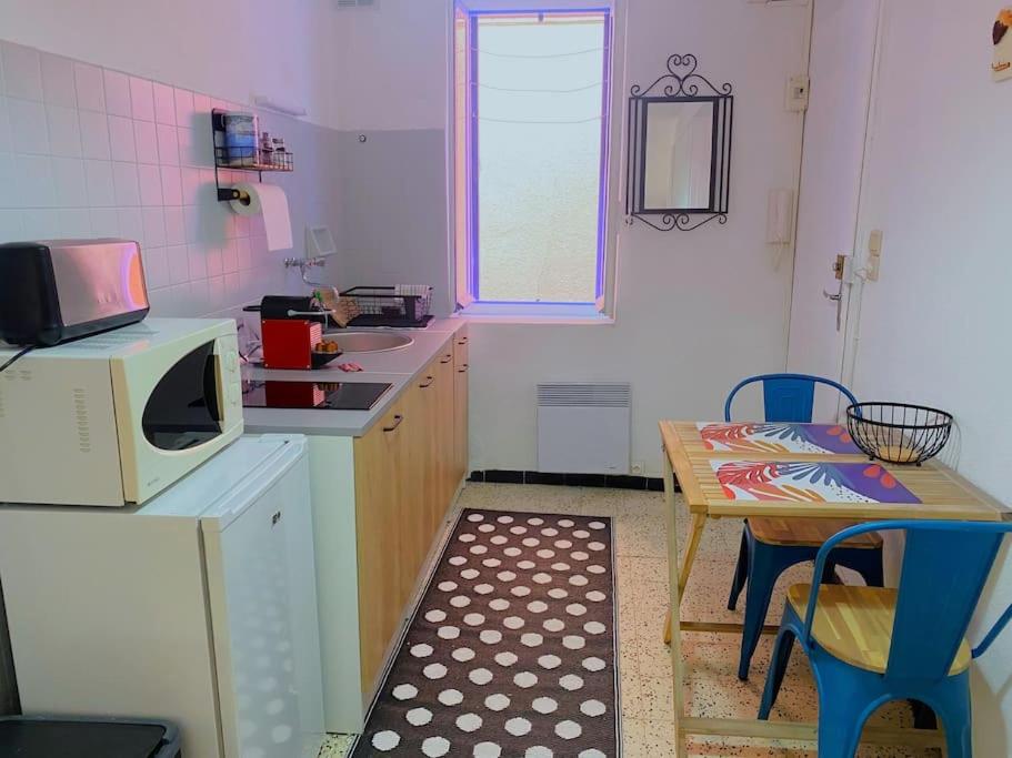 a small kitchen with a table and a microwave at À deux pas de la plage in Collioure