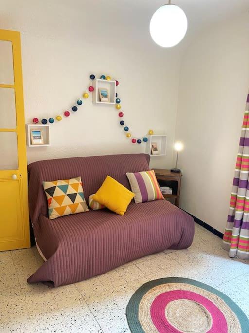 a living room with a purple couch with colorful pillows at À deux pas de la plage in Collioure