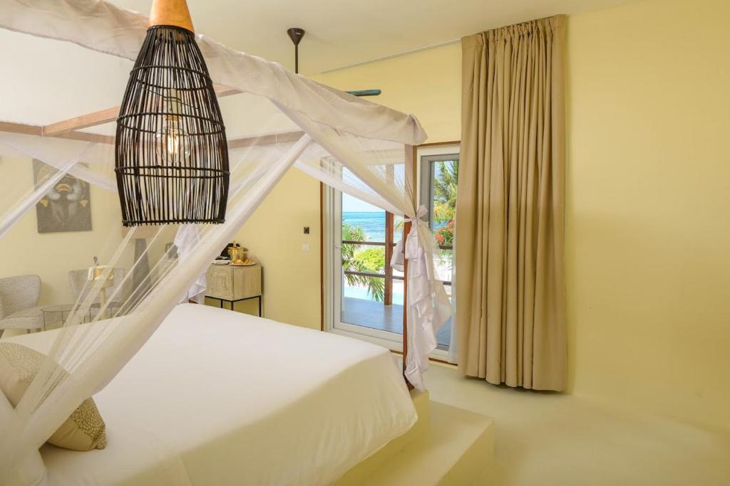 Alma Boutique Hotel في جامبياني: غرفة نوم بسرير ابيض ونافذة
