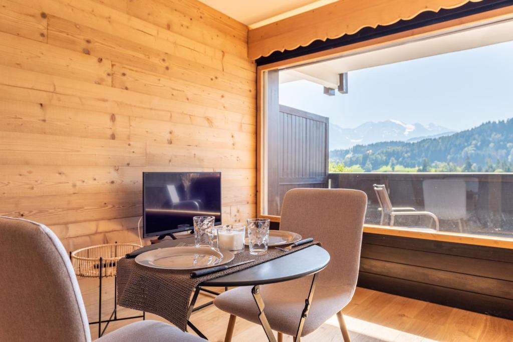 une salle à manger avec une table, des chaises et une télévision dans l'établissement Le Balcon du Mont Blanc - Studio refait à neuf, à Cordon