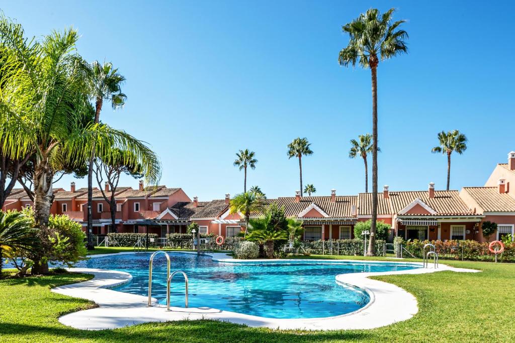 a swimming pool at a resort with palm trees at Ático Novo Sancti in Chiclana de la Frontera