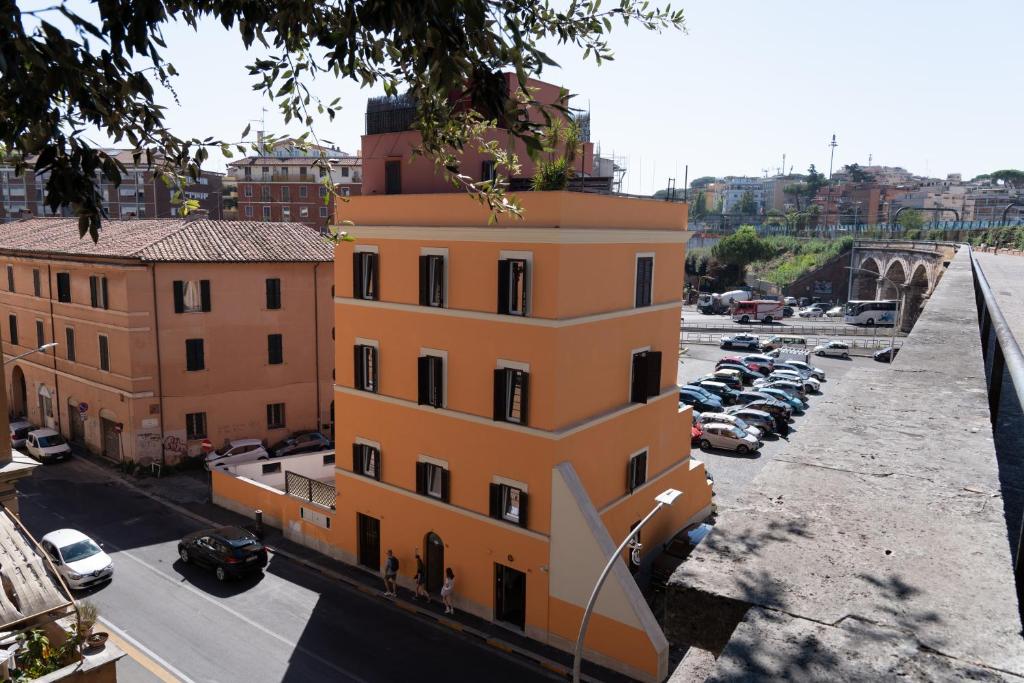 un bâtiment jaune avec des voitures garées dans un parking dans l'établissement Hotel VM, à Rome