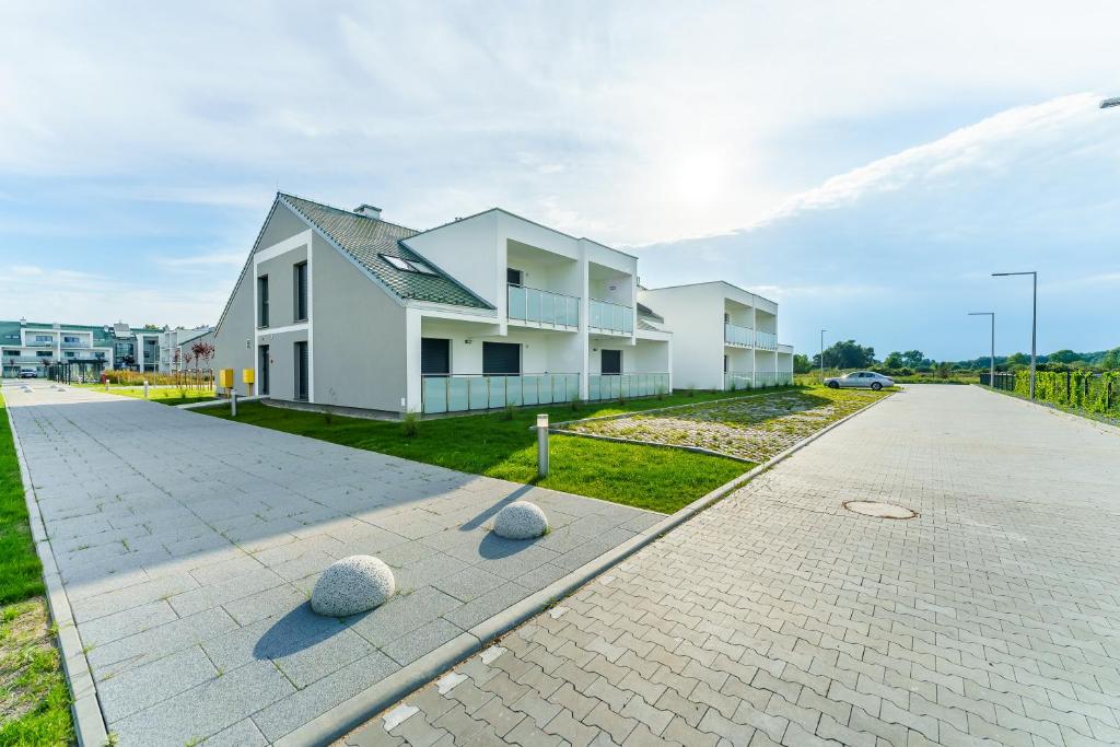 een groot wit huis met een oprit bij Sunset Resort IV, Nadmorska 98B in Grzybowo