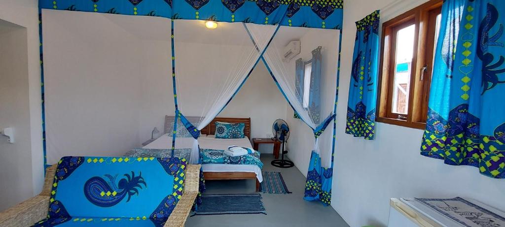 - une chambre avec un lit dans une pièce dotée de rideaux bleus dans l'établissement Neptune's Lodge and Beach Bar, à Cabo Nhamua