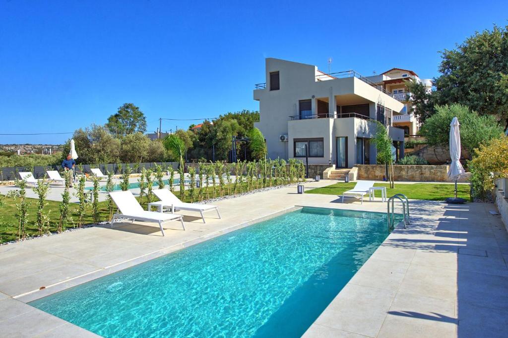 a villa with a swimming pool in front of a house at Phaedra by PosarelliVillas in Kounoupidhianá