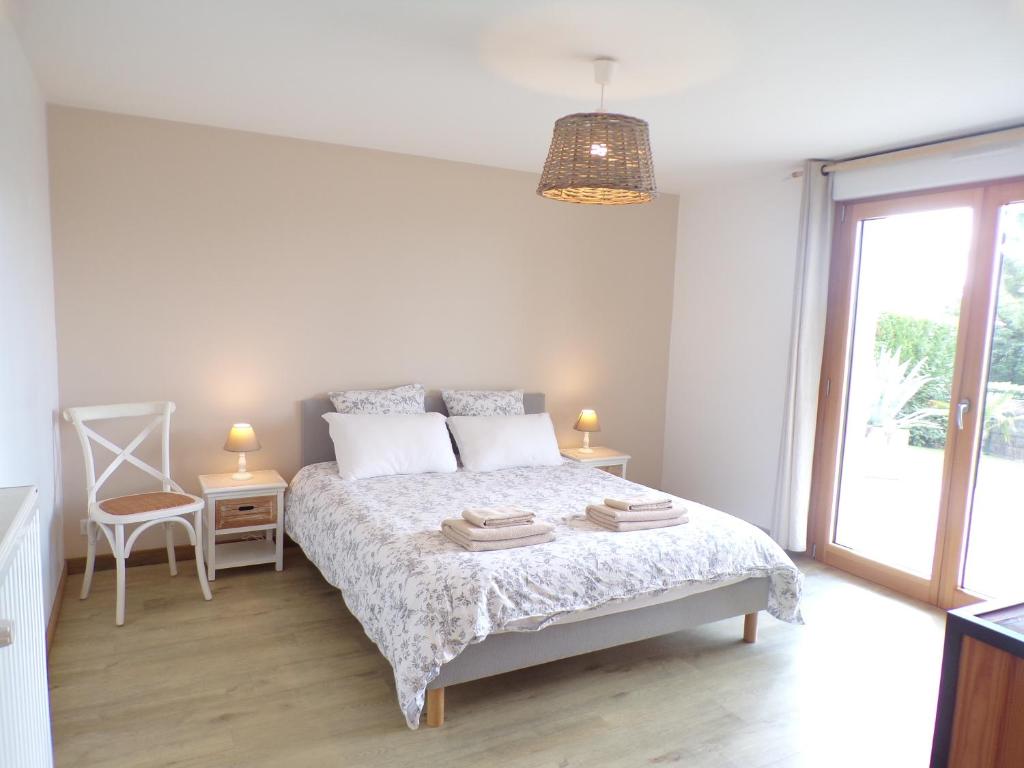 una camera bianca con un letto e una sedia di Le Cocon de l'Estuaire, T2 confort, bord de plage et paysages a Saint-Jouan-des-Guérets