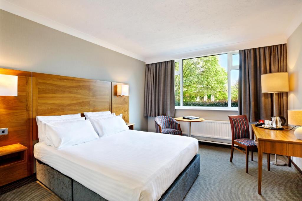 ハダーズフィールドにあるCedar Court Hotel Huddersfieldの大きなベッドとデスクが備わるホテルルームです。