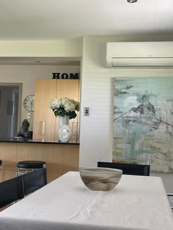 a dining room with a table with a vase on it at Secluded Bays Home in Auckland