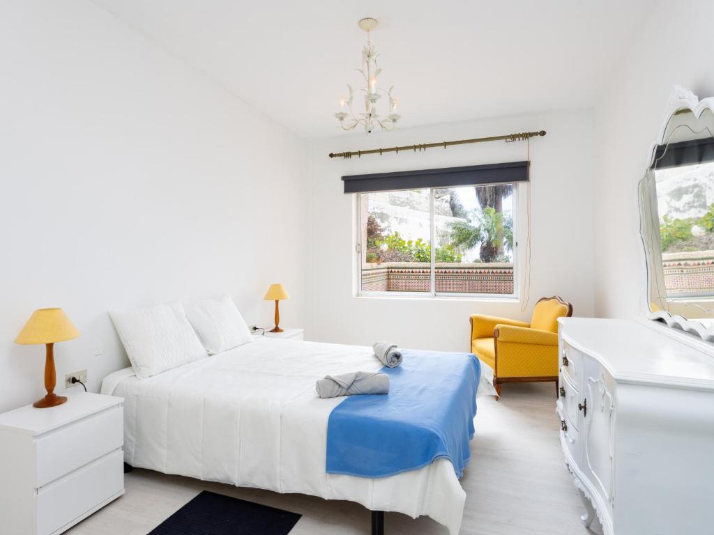 um quarto branco com uma cama e uma cadeira amarela em Live Playa San Marcos Sayris Sea em Icod de los Vinos