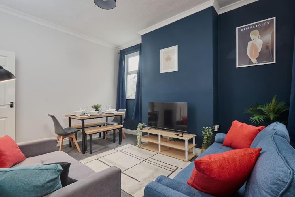 a living room with blue walls and a blue couch at Spacious 3-Bedroom House With Garden and Parking in Stockton-on-Tees