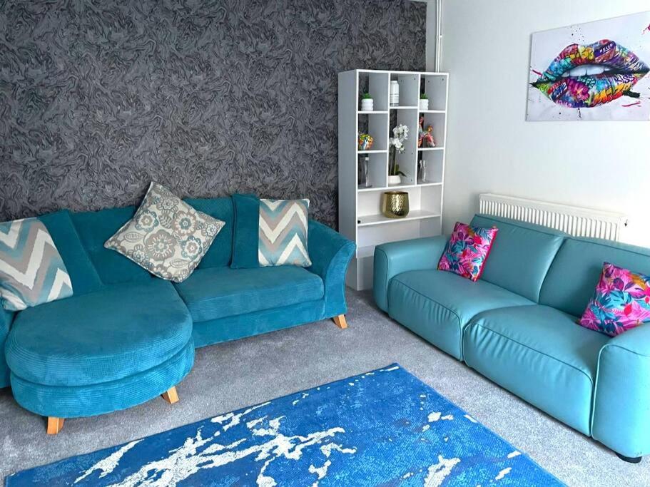 a living room with a blue couch and two couches at 4-bedroom home with off-road parking in Swansea