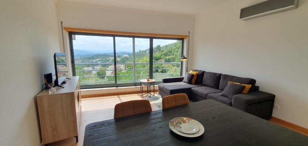 ein Wohnzimmer mit einem Tisch und einem großen Fenster in der Unterkunft Coimbra's Black & Gold in Coimbra