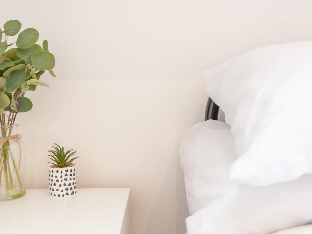 a white bedroom with a plant in a vase on a table at Pass the Keys The Couples Nest close to Leeds city centre in Leeds