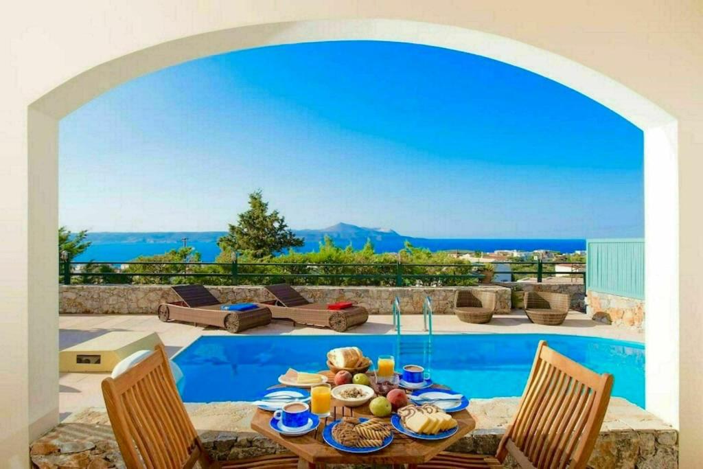 a dining room with a table and a view of the ocean at Villa Persephone by PosarelliVillas in Plaka