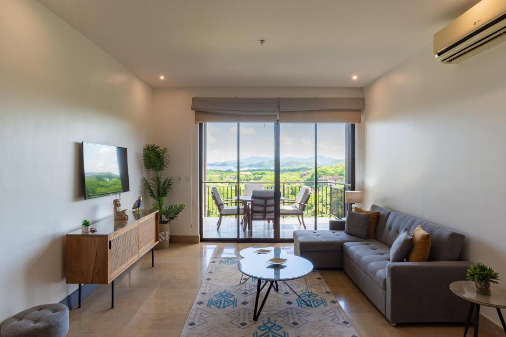 a living room with a couch and a table at Roble Sabana 404 Luxury Apartment Adults Only - Reserva Conchal in Playa Conchal