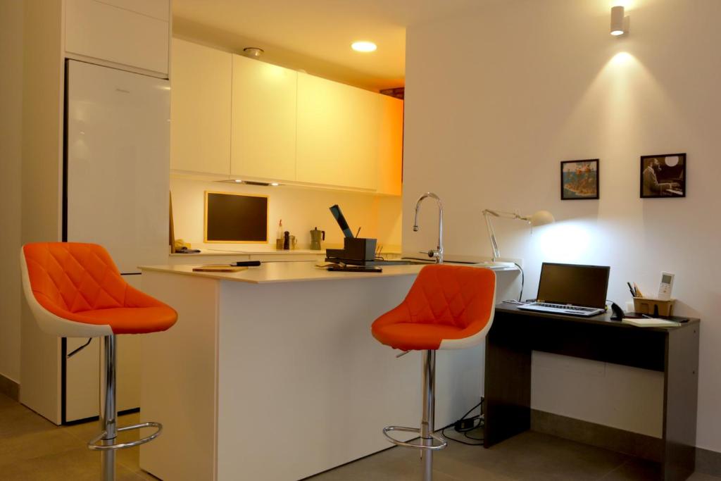 cocina con sillas de color naranja y escritorio con ordenador portátil en Apartment with two Suites in the Center of Malaga, en Málaga