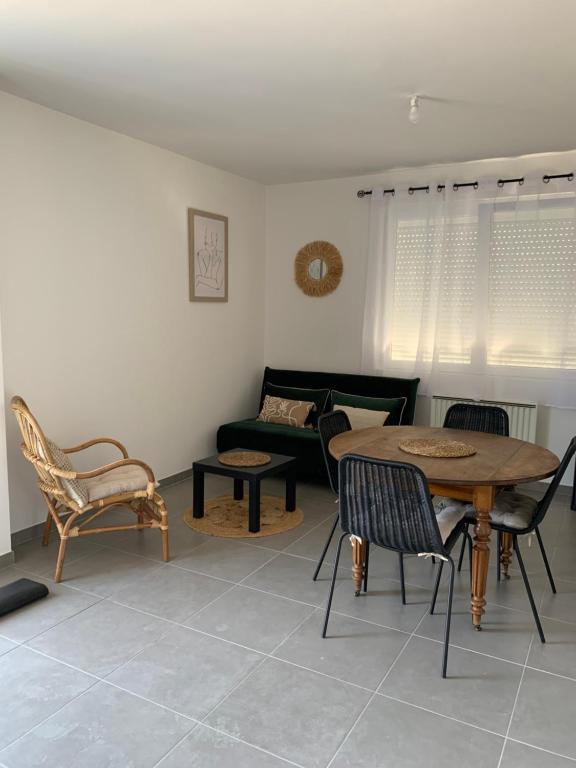 un soggiorno con tavolo, sedie e divano di Chez Claudine APPART COSY a Château-Gontier