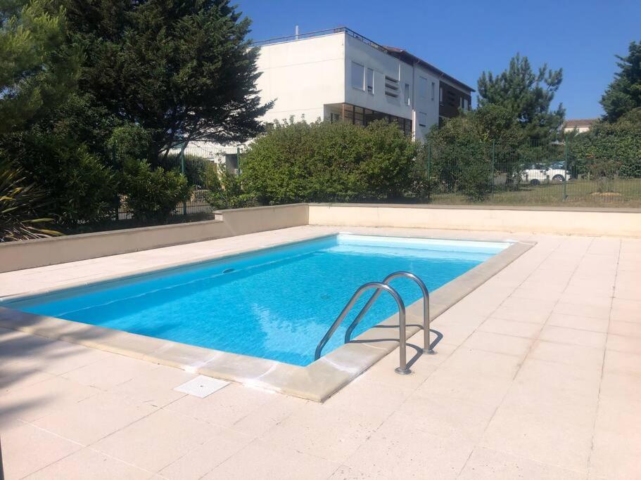 - une piscine avec une chaise en face d'un bâtiment dans l'établissement T2 avec piscine et terrasse dans résidence arborée, à La Rochelle