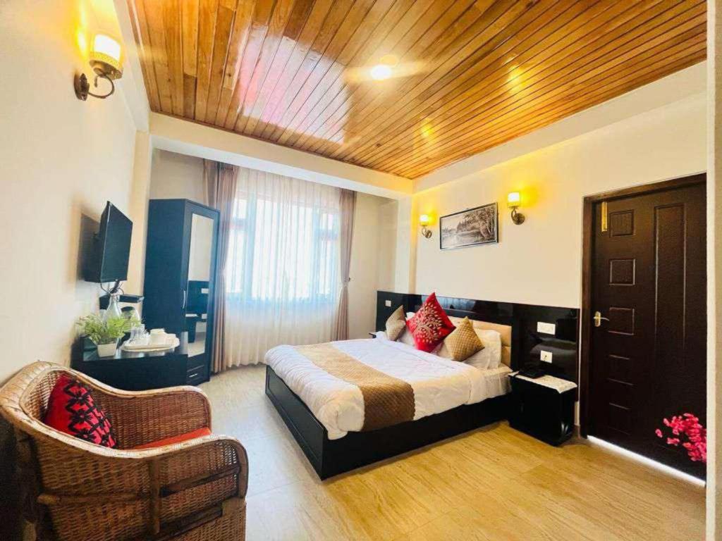 a bedroom with a bed and a chair in it at Maplewood Hotel & Spa in Gangtok