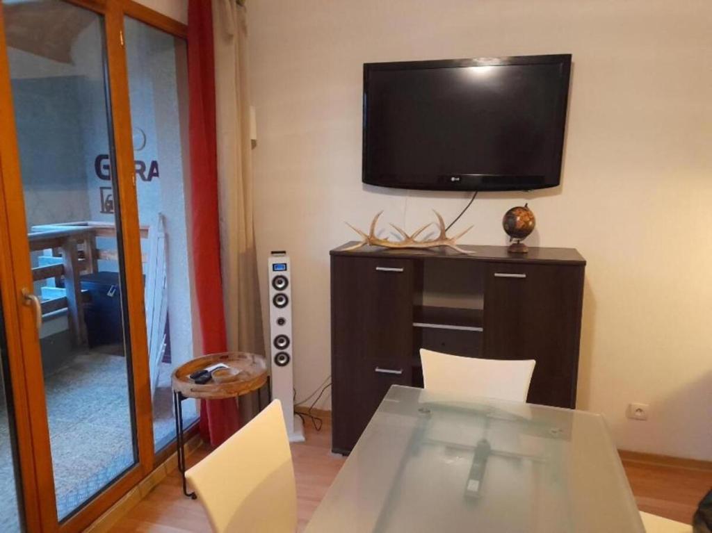 Habitación con mesa y TV en la pared. en studio montagne en Les Orres