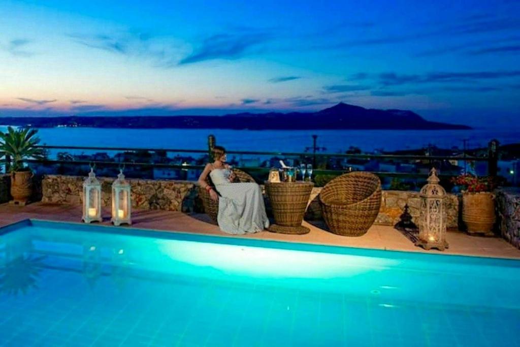 a bride and groom sitting on the ledge of a resort at Villa Aphrodite by PosarelliVillas in Plaka