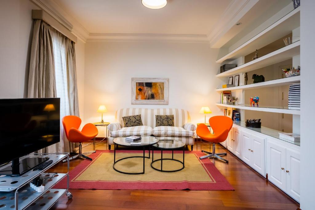 ein Wohnzimmer mit einem Sofa, Stühlen und einem TV in der Unterkunft Amplio y luminoso-2D 2B-Triana in Sevilla