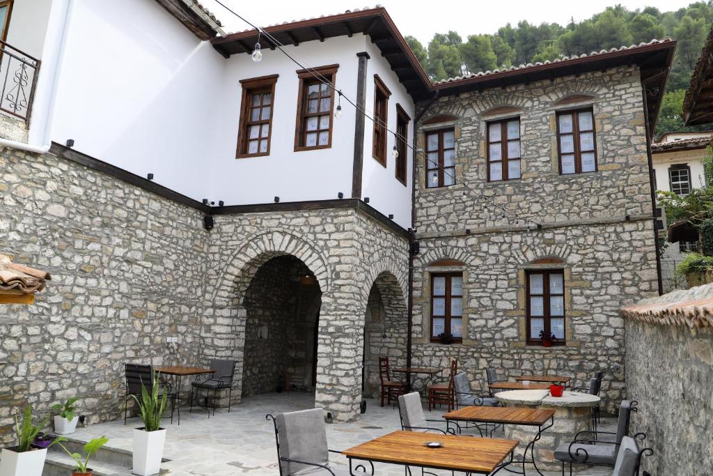 un patio al aire libre con mesas y sillas en un edificio de piedra en Koroni Boutique Hotel, en Berat
