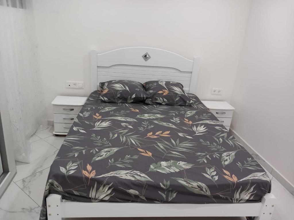 een slaapkamer met een bed met een sprei met zwarte bloemen bij Edifício 2PALMA in Praia